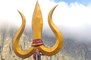 Trident weapon of lord shiva placed ahead of a cloudy mountain-image