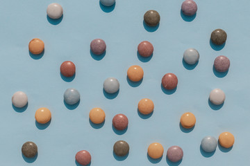 Blue background with multi-colored dragees scattered on the surf