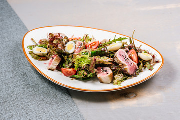 Tasty fresh salad with meat and vegetables on the wooden background