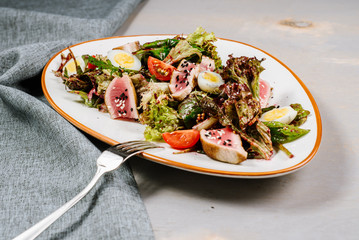 Tasty fresh salad with meat and vegetables on the wooden background