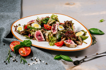 Tasty fresh salad with meat and vegetables on the wooden background