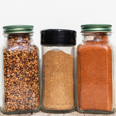 Three jars with spices of different grinding on a white backgrou