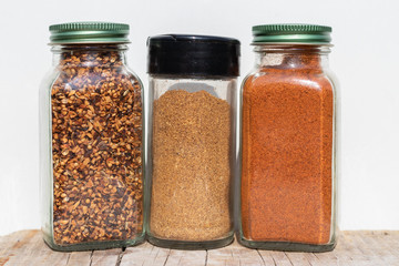 Three jars with spices of different grinding on a white backgrou