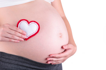 Pregnant women holding heart symbol placed on belly isolated on white background
