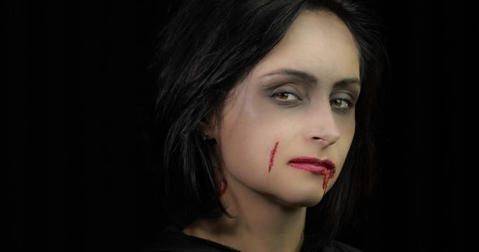 Vampire Halloween makeup. Woman portrait with blood on her face.