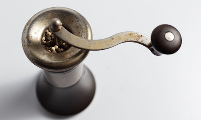 Close-up of ancient pepper mill on white background.