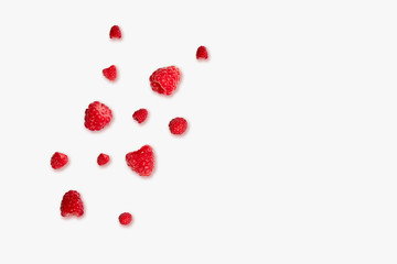 Ripe red raspberries berries randomly lie on a pink background. Summer health concept.