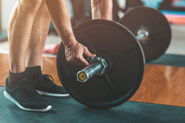 Obraz premium Cropped portrait of man going to lift barbell while having a workout in gym. Horizontal shot