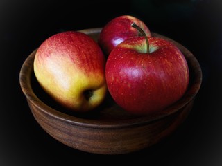 Three apples in a bowl on a black background