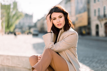 Outdoor portrait of young beautiful fashionable lady posing on the background of old morning city....