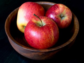Three apples in a bowl on a black background
