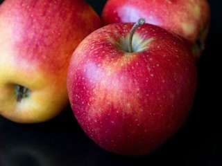 Three red apples on a black background, close-up