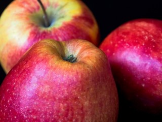 Three red apples on a black background, close-up, detail