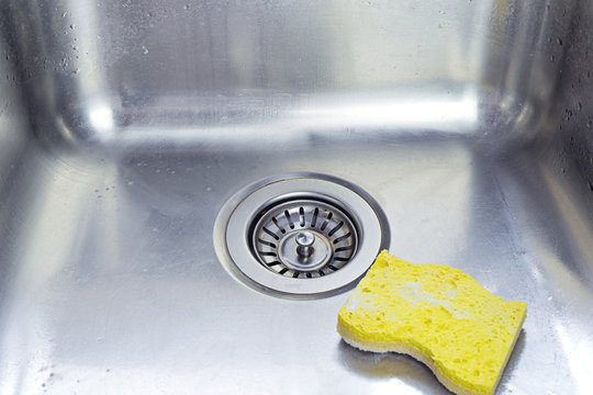 Cleaning polished stainless shiny sink with scrub sponge