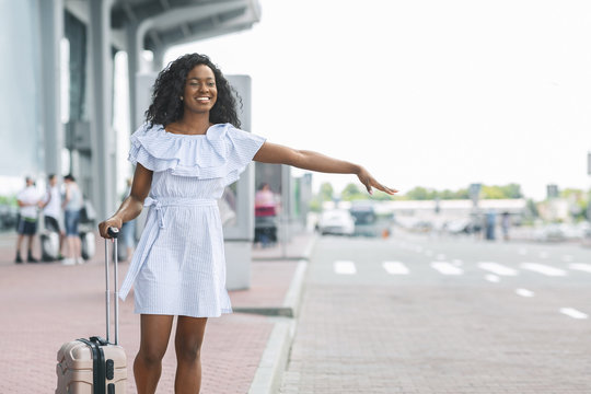 Young african woman waving hand near airport building