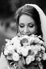 Bride with bouquet. Beautiful brunette bride makeup and hairstyle in luxury dress. The bride is holding a wedding bouquet of unusual beautiful flower.  Fashion bride. Black and white