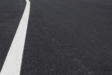 Low angle perspective view of white curved paint line on asphalt road