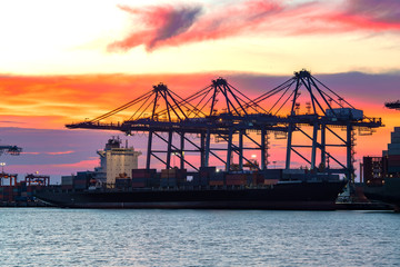 Obraz premium Cargo freight ship and cargo container working with crane at port area,Logistic Import Export at sunset,Thailand 4.0