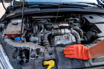 Human hands with oil level meter against car engine