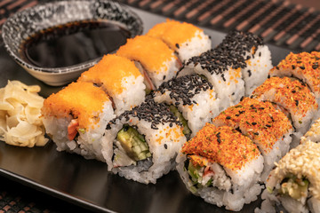 variety of sushi rolls served with soy sauce on table