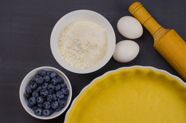 shortbread dough for baking quiche tart and ingredients in baking form with berries. baking concept