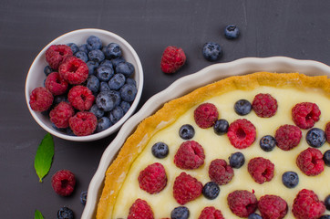 Delicious Blueberry tartlets with vanilla cream on black wooden background. Top view. confectionery concepts, bakery concept