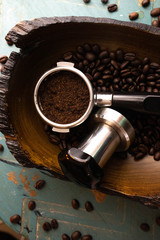 Espresso portafilter and tamp with Arabica coffee beans in a burl heritage wood bowl. 