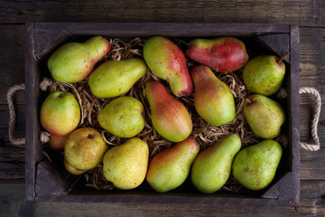 Fresh green pear. Assortment of pears in a wooden box. On the black table. Free space for text. Top view.