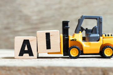 Toy forklift hold letter block i to complete word AI (Abbreviation of Page artificial intelligence) on wood background