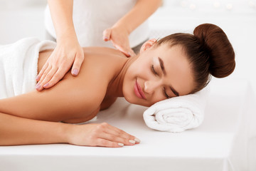 Fototapeta na wymiar Relaxed girl enjoying back massage in spa salon