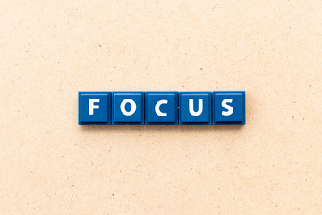 Tile letter in word focus on wood background
