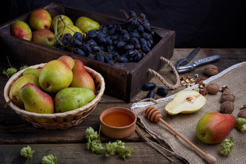 Flat lay with a pears with walnuts on dark wooden background. With hops and honey. Grape.