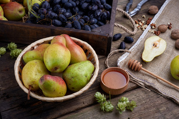 Flat lay with a pears with walnuts on dark wooden background. With hops and honey. Grape.