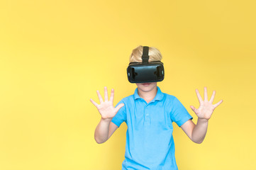Children experiencing virtual reality isolated on yellow a background. Surprised little boy looking in VR glasses.