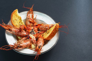 dishes with langoustines, in a plate on a black background. view from above. copyspace.