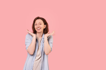 Pretty well-groomed cheerful woman focuses on her face posing on a pink background. Young woman advertises cosmetics and beauty treatments. Advertising space