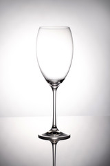 Empty wine glass goblets stands on a mirror surface on white background
