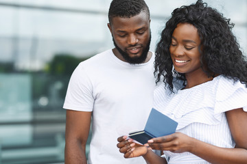 Millennial black couple checking tickets in front of airport entrance