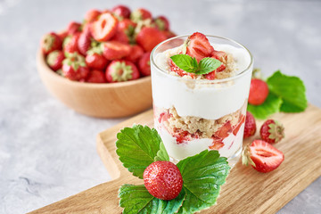 Strawberry granola or smoothie in a glass and fresh berries in wooden bowl, top view. Healthy breakfast