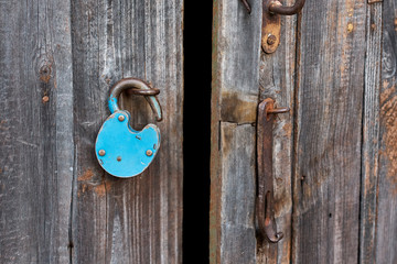 Blue old rusty unlocked padlock on wooden door