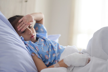 Patient child laying on hospital bed with saline solution intravenous
