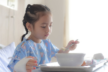 Patient child eating food in hospital bed
