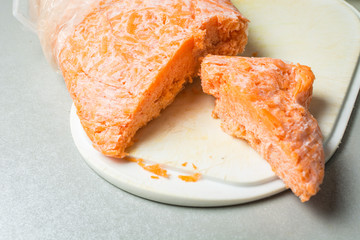 Cut frozen carrots for cooking grilling on kitchen board.