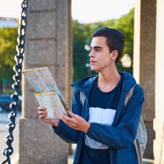 Young man standing on street of big city and looking at guide, a tourist in St. Petersburg looking for a route