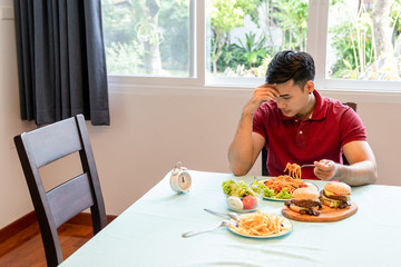 Handsome man sit and waited for his wife come back to home. He sat there waiting for her come to have lunch in the kitchen at the house with he. Being punctual is an important part of living together.