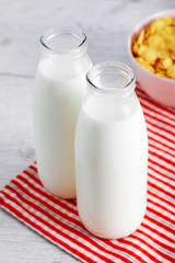 Milk bottles and cereal corn flakes on wooden table. Close up view from above.
