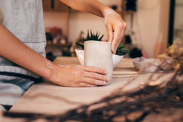 Hands of a woman potter making a clay mug. Craftswoman moulding clay with hands.