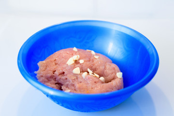 minced chicken with garlic in a blue bowl on a white background