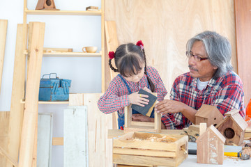 Asian carpenter and his daughter are designing and creating woodwork at carpentry workshop. Family...