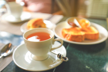 Blurred image of a cup of hot tea  and toasts on table